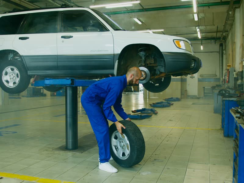 Mecánico retirando una rueda de un vehículo elevado